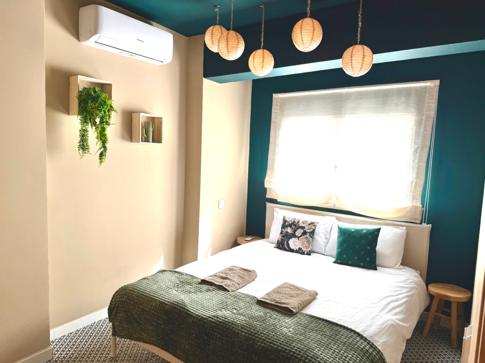 Chambre aux murs crème et touches turquoise. Luminaires suspendus et décor minimaliste.