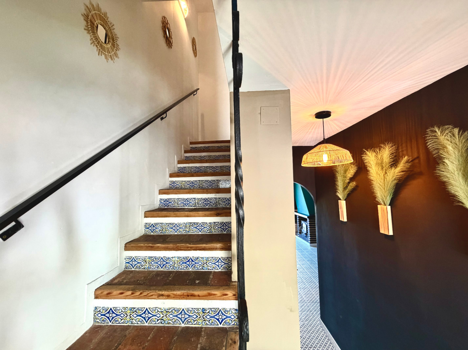 Détail d'escalier avec carreaux décoratifs, mur avec miroirs et appliques design.
