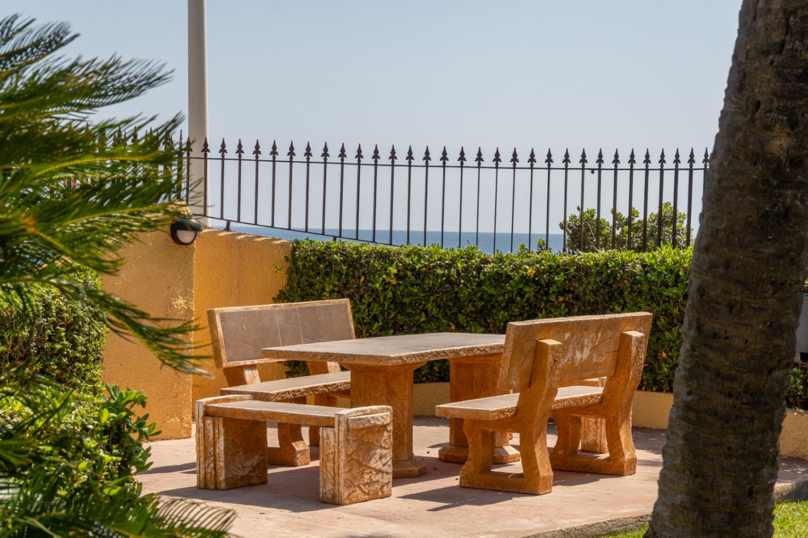 Patio avec table en pierre et vue sur mer dans une urbanisation paysagée à Jávea.