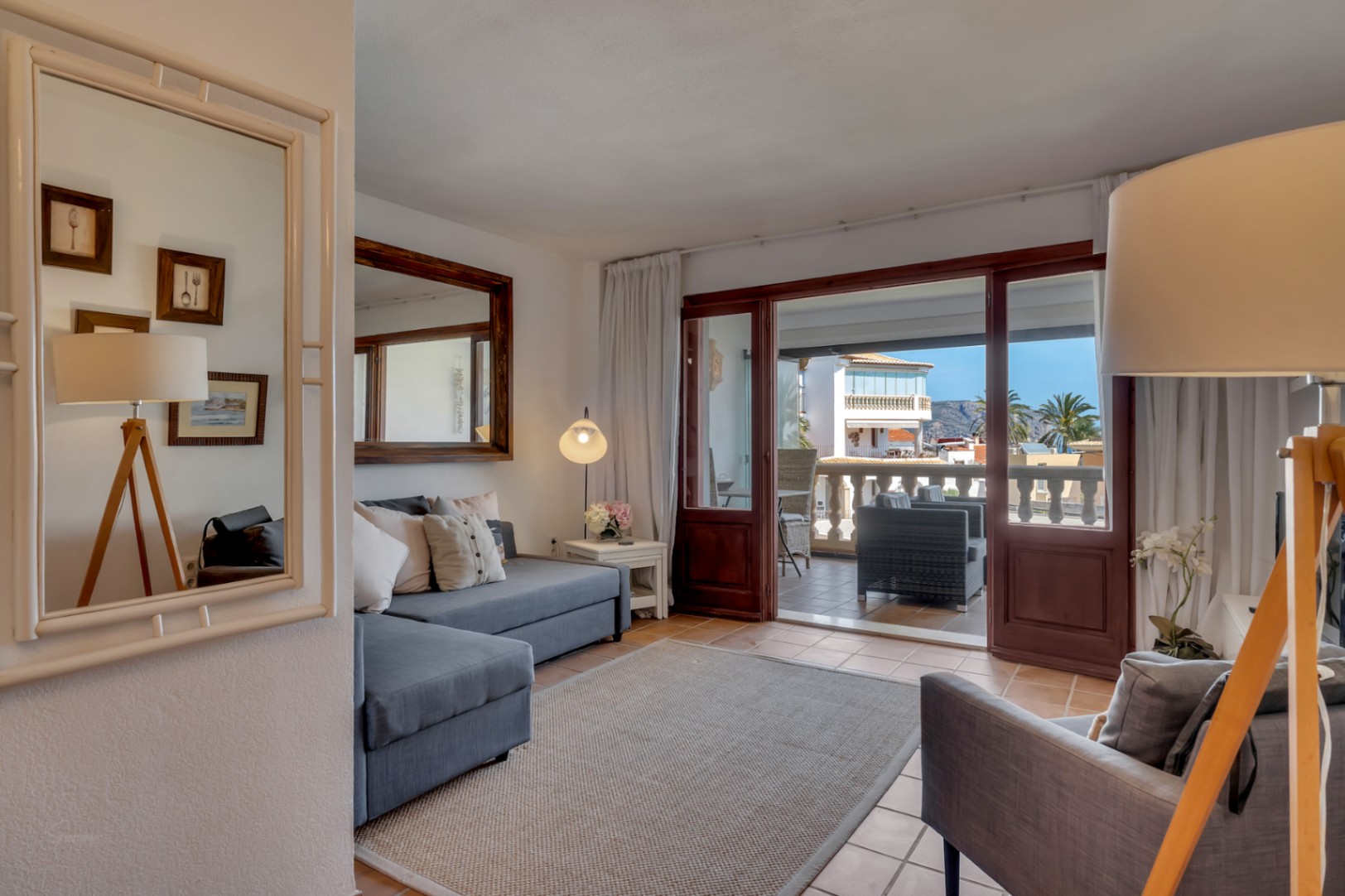 Salon lumineux avec terrasse vitrée et vue sur la mer à Jávea. Canapé gris et décor neutre.