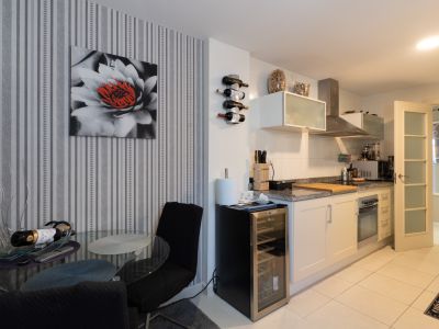 Cuisine moderne avec plan de travail en granit, appareils intégrés et casier à vin. Une cave à vin et une table à manger en verre agrémentent le mur à rayures.