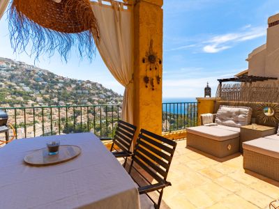 Grande terrasse extérieure aménagée avec table à manger, barbecue et salon de jardin, offrant des vues panoramiques sur la colline résidentielle et la mer Méditerranée.