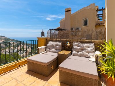 Terrasse avec chaises longues en rotin, carrelage couleur terre cuite et vues panoramiques sur la mer Méditerranée et les collines d'Altea.