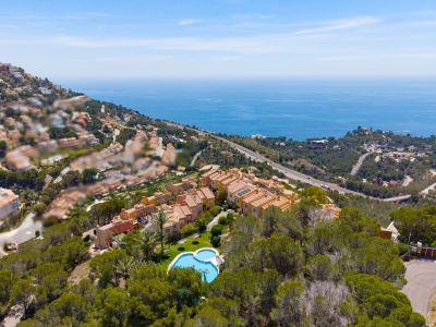Vue aérienne d'un complexe résidentiel en colline avec piscine en forme de cœur, entouré d'arbres, offrant une vue panoramique sur la mer Méditerranée.