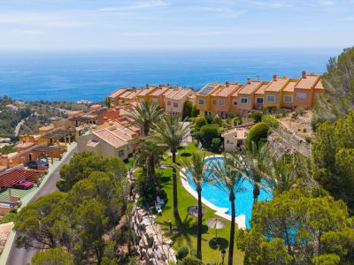 Vue aérienne d'un complexe résidentiel en terrasses avec grande piscine commune, palmiers matures et vues étendues sur la mer Méditerranée.