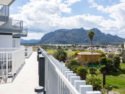 Grande terrasse avec balustrade blanche moderne, offrant des vues panoramiques sur la majestueuse montagne du Montgó, la verdure luxuriante et les toits méditerranéens.