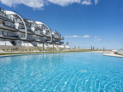Piscine extérieure bleu vif dans un complexe moderne avec architecture courbée, balcons vitrés et vue lointaine sur la mer.