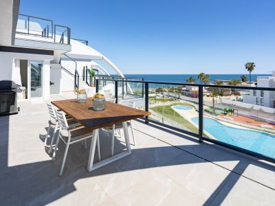 Vaste terrasse extérieure avec table à manger en bois et barbecue, offrant une vue panoramique sur la mer Méditerranée et les piscines communes.