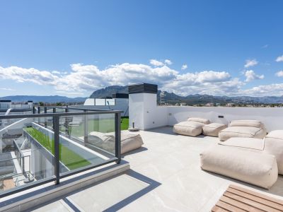 Vaste terrasse sur le toit avec carrelage clair, poufs beiges confortables, balustrades en verre et vues panoramiques sur les montagnes.