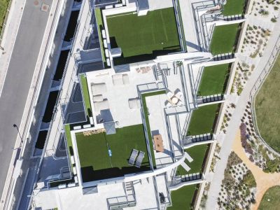 Vue aérienne de terrasses de toit modernes avec gazon artificiel, mobilier de salon extérieur et zones repas, près des sentiers et d'une piscine.