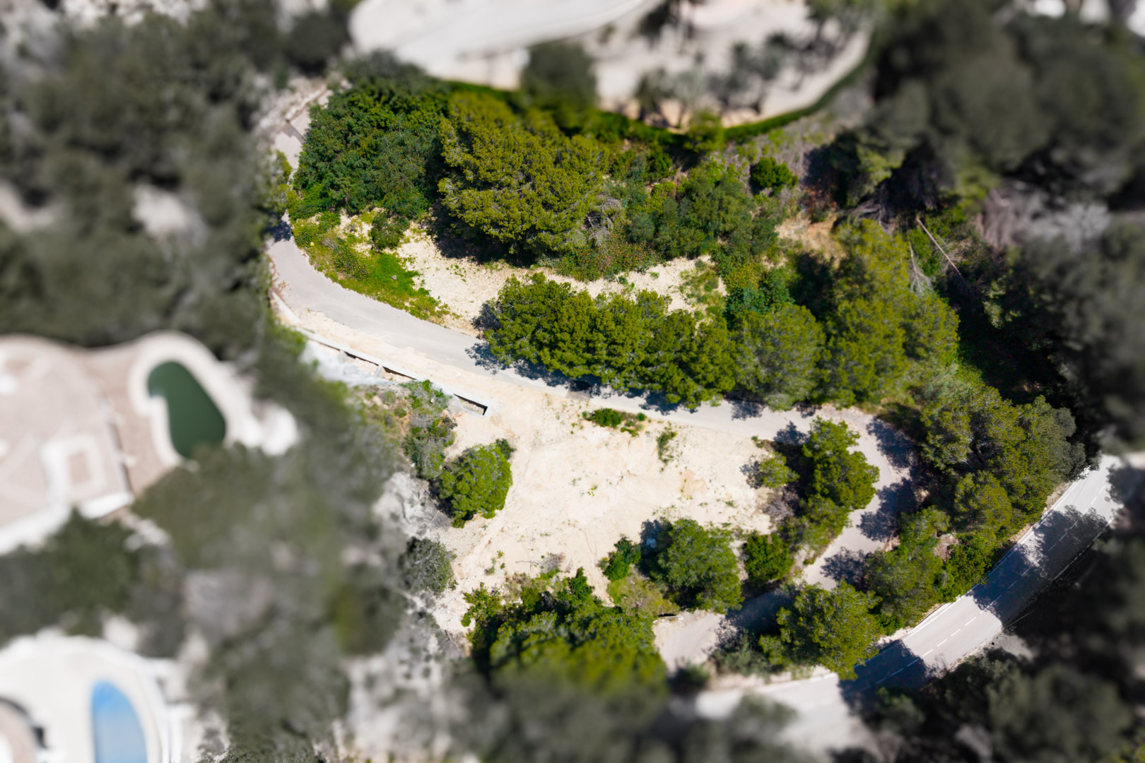 Vue aérienne d'une parcelle à Mar Azul, Jávea, présentant un terrain non bâti entouré de verdure.
