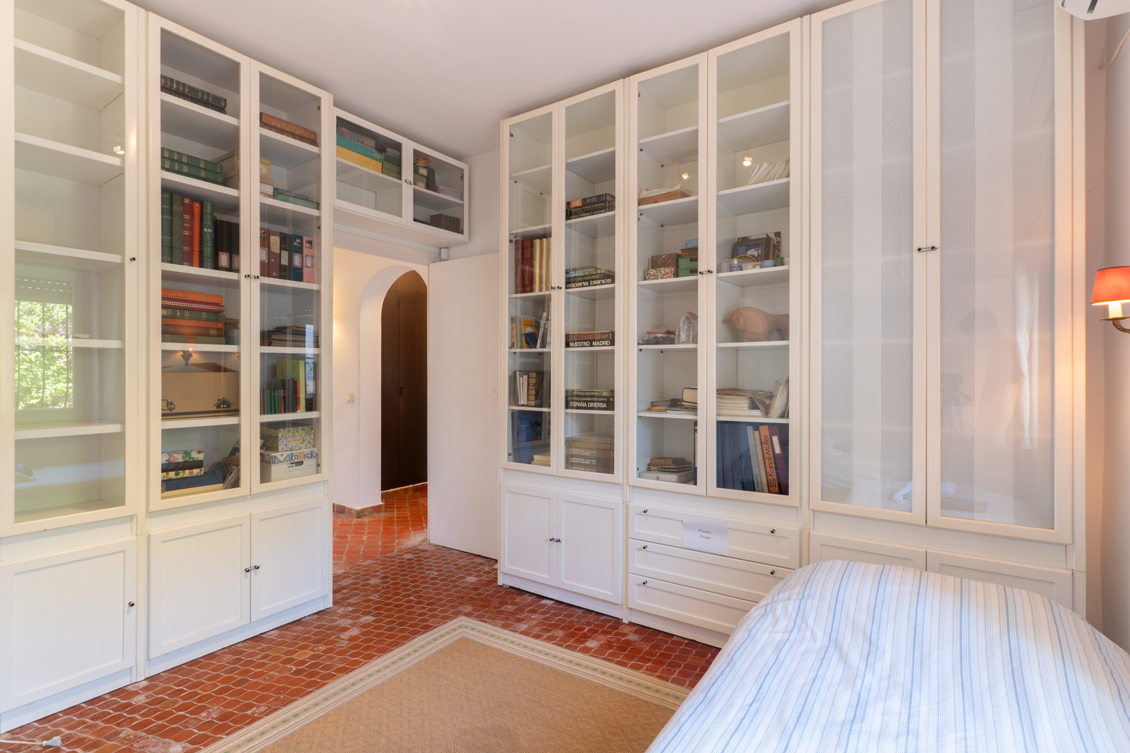 Chambre avec étagères blanches intégrées et sol en terre cuite.