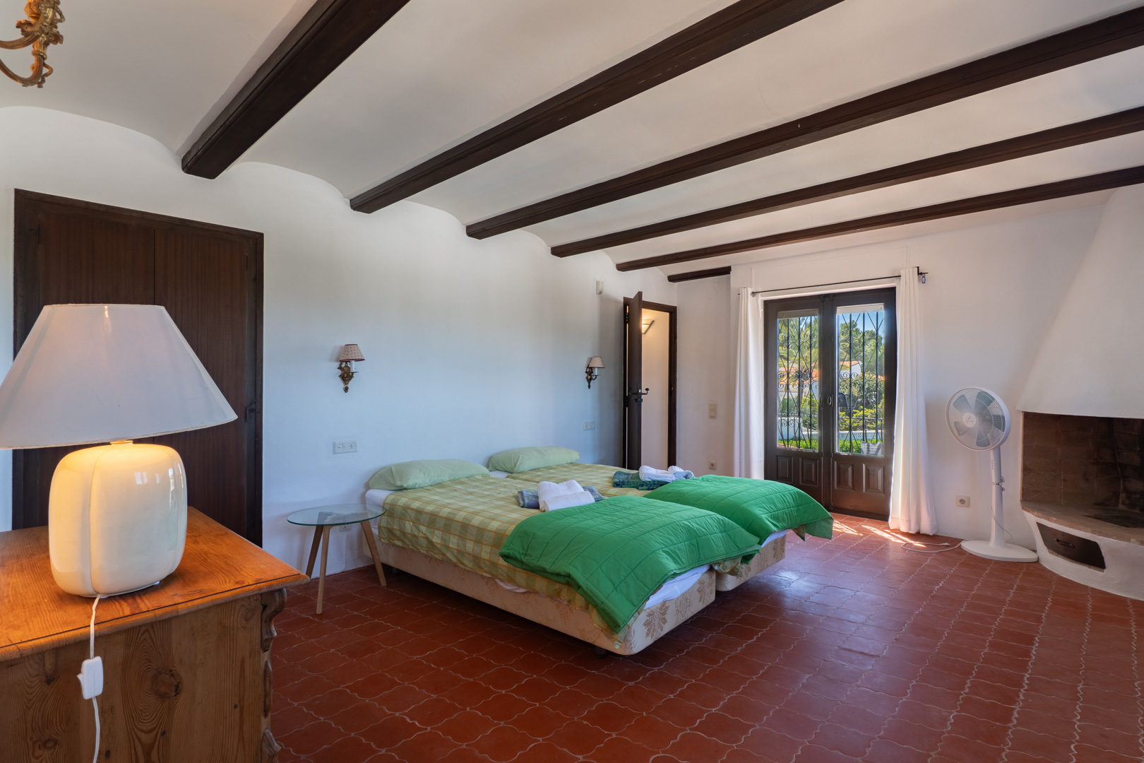 Chambre avec lits jumeaux, poutres apparentes et sol en terre cuite.
