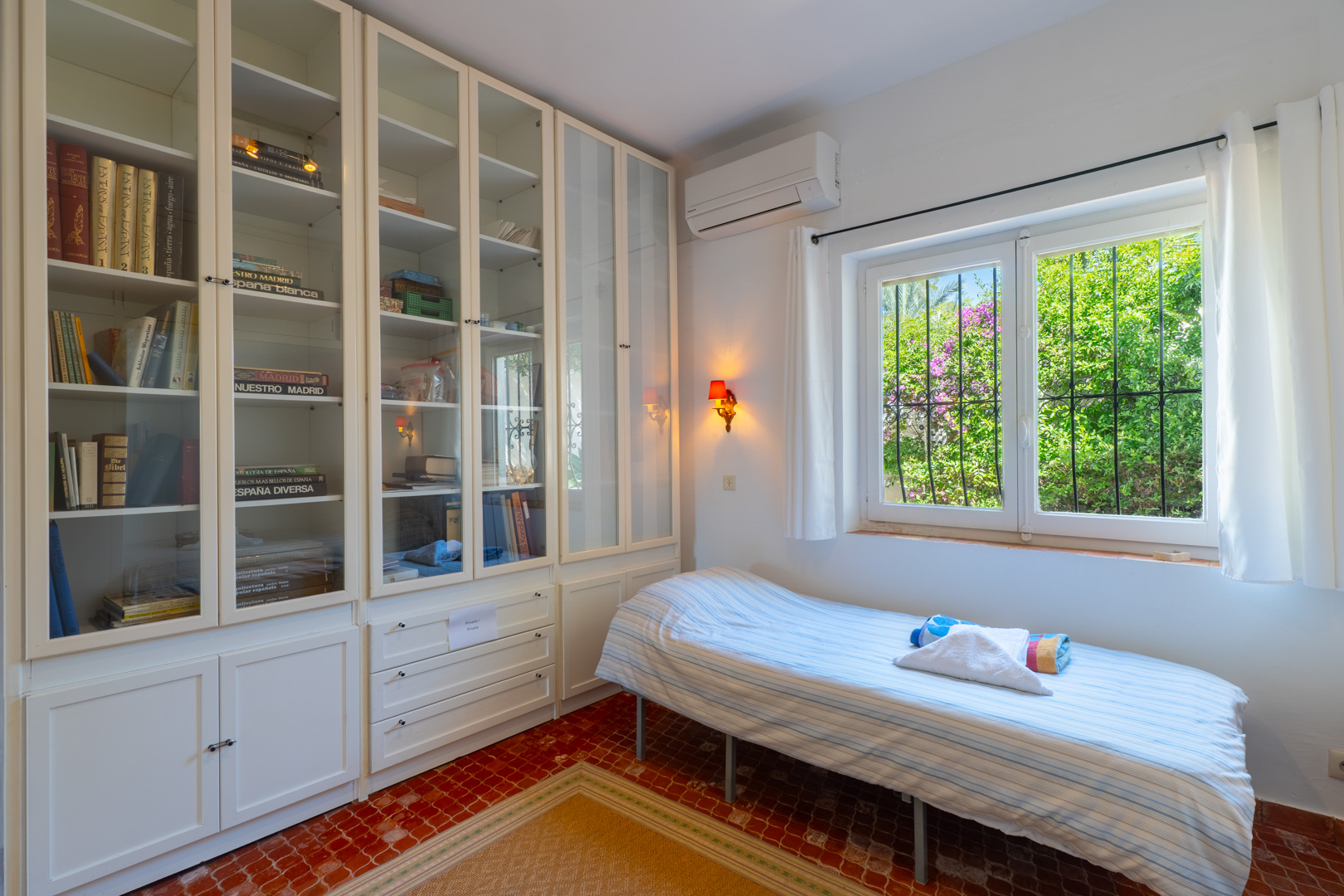 Chambre lumineuse avec étagères intégrées et vue sur le jardin.
