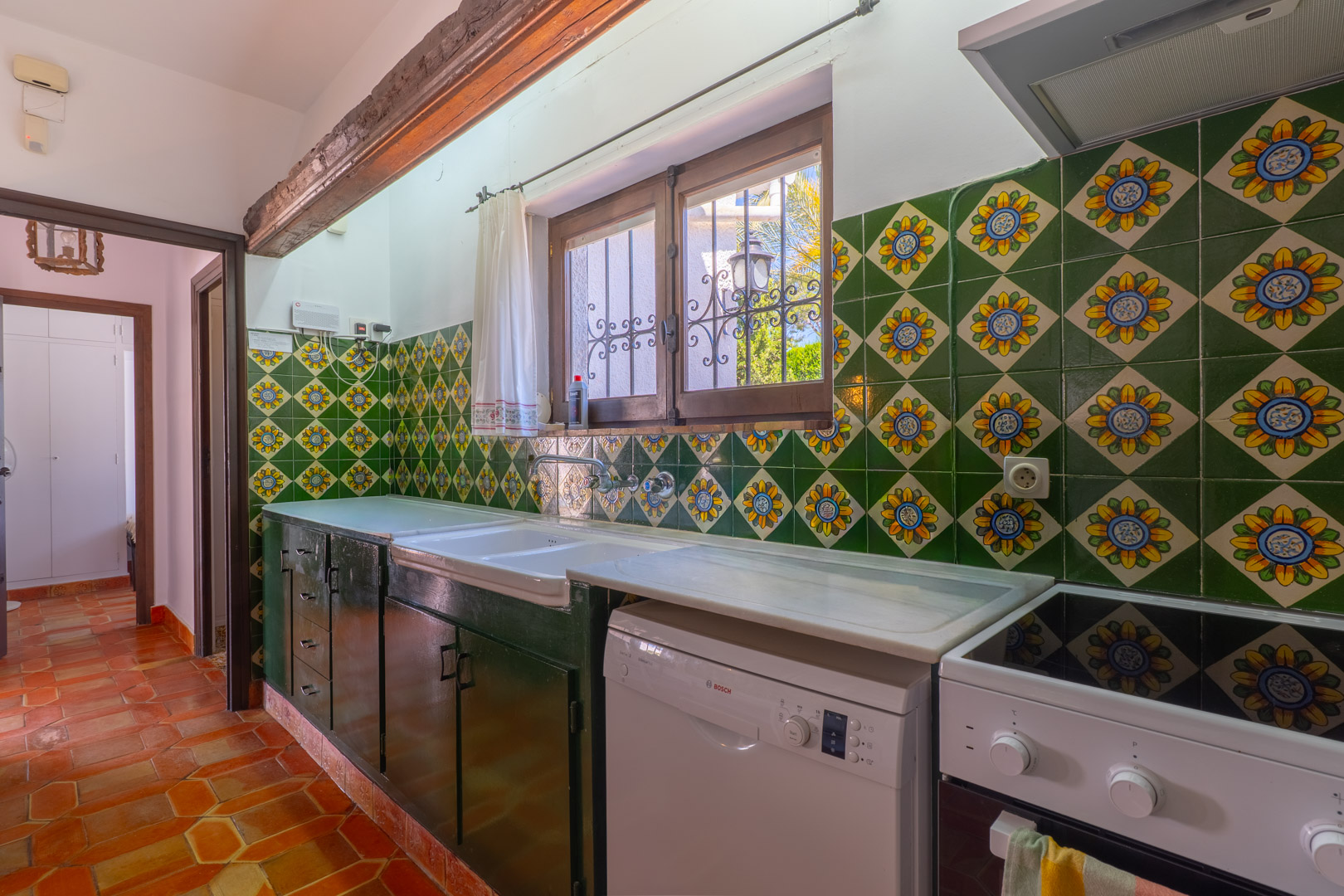 Cuisine rustique avec carrelage décoratif, comptoir en marbre et sol en terre cuite.