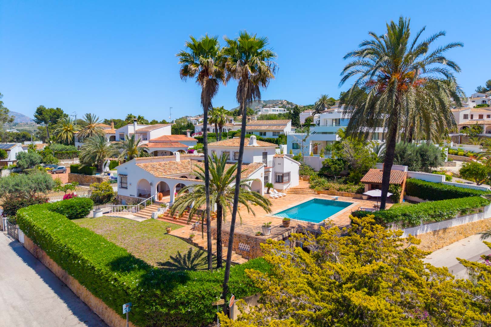Vue aérienne de la villa avec piscine entourée de jardins et de palmiers.