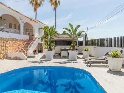 Vue extérieure de la villa 'Casa Alta' avec piscine en mosaïque bleue. La terrasse en lames claires entoure la piscine, près d'un escalier extérieur aux carreaux décoratifs et base en pierre.