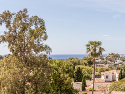Vue panoramique depuis la villa, avec la mer Méditerranée à l'horizon, une végétation luxuriante et des maisons résidentielles aux toits de tuiles.