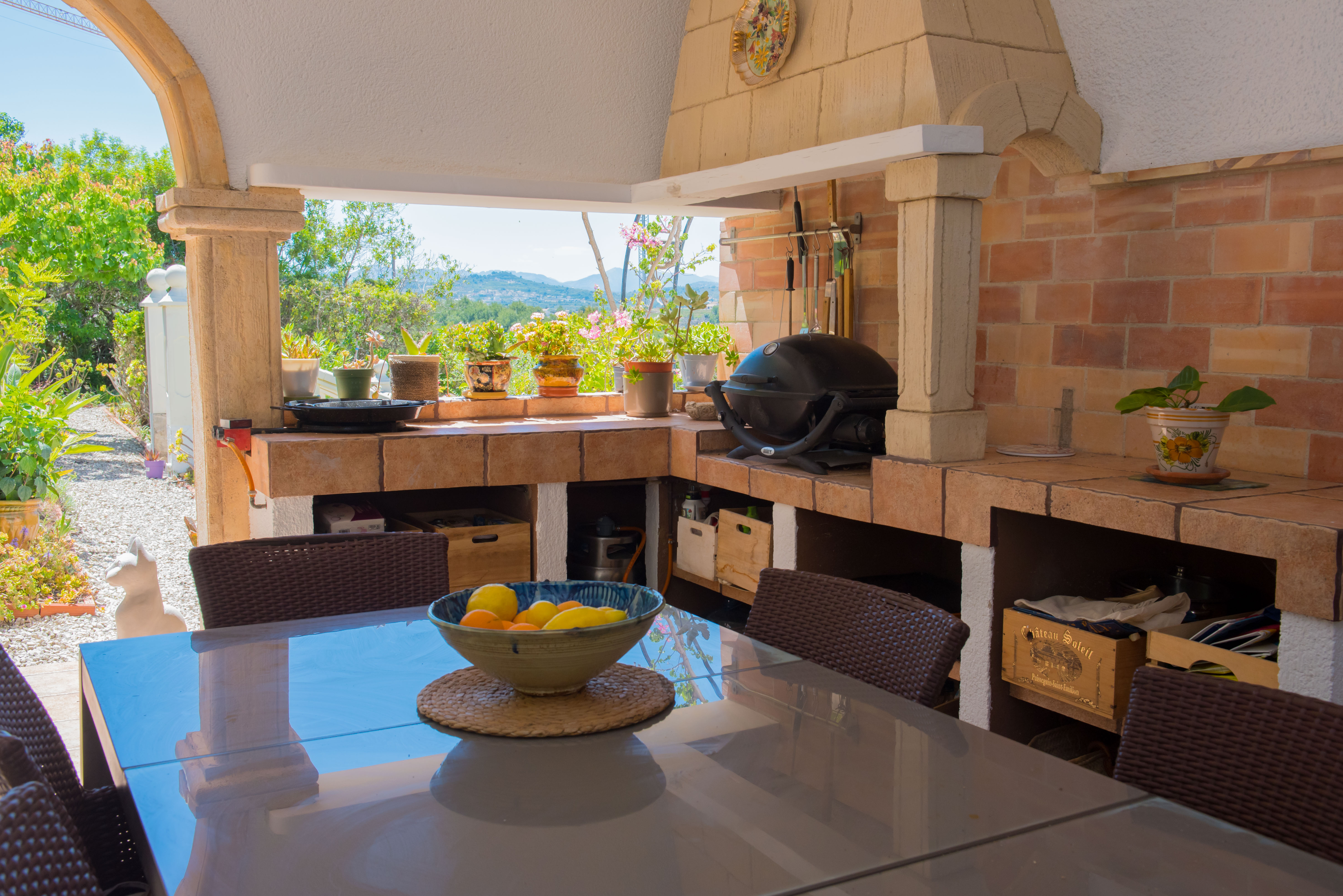 Coin barbecue extérieur avec four en briques et table à manger donnant sur le jardin.