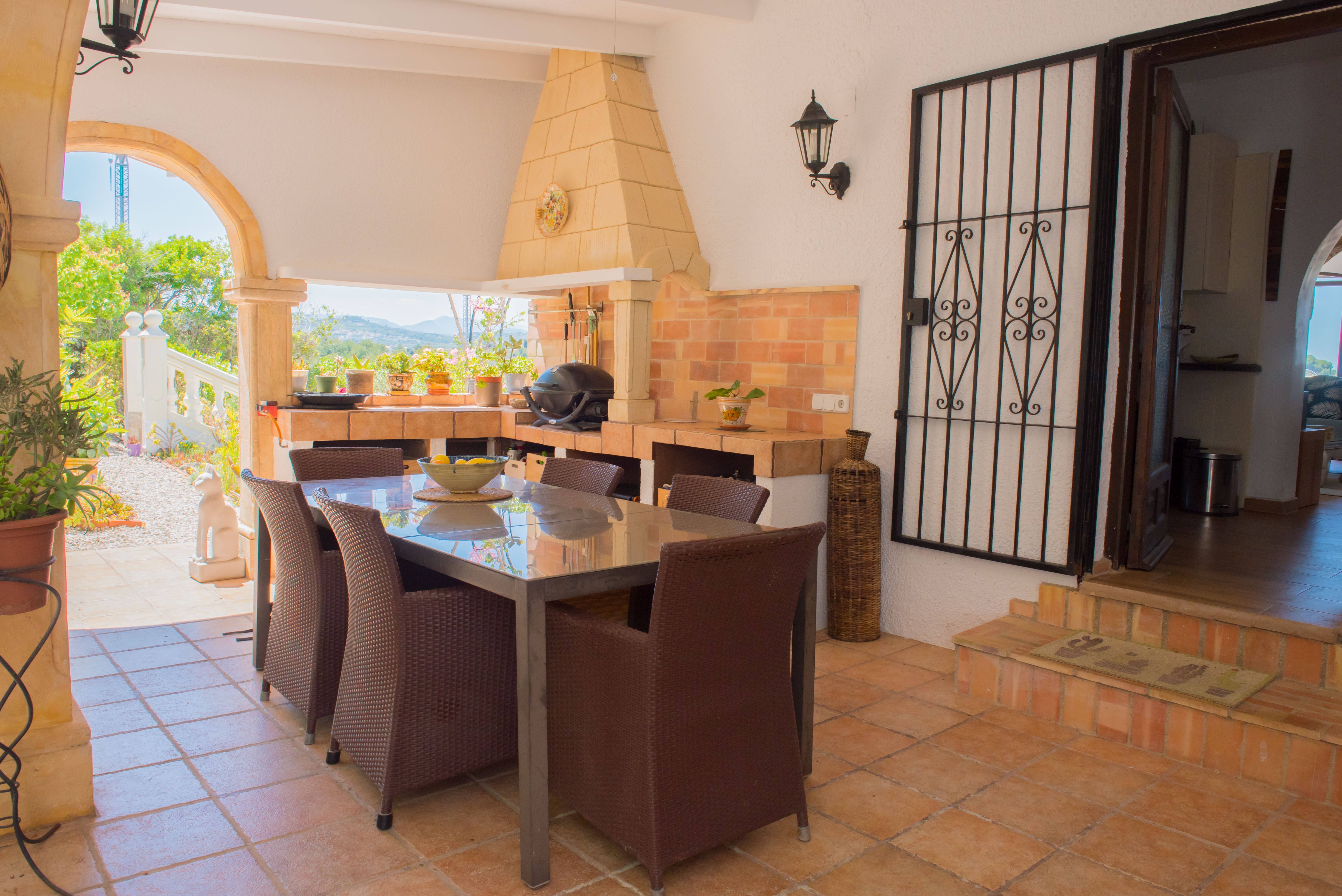 Salle à manger extérieure couverte avec barbecue en brique et table en acier inoxydable.