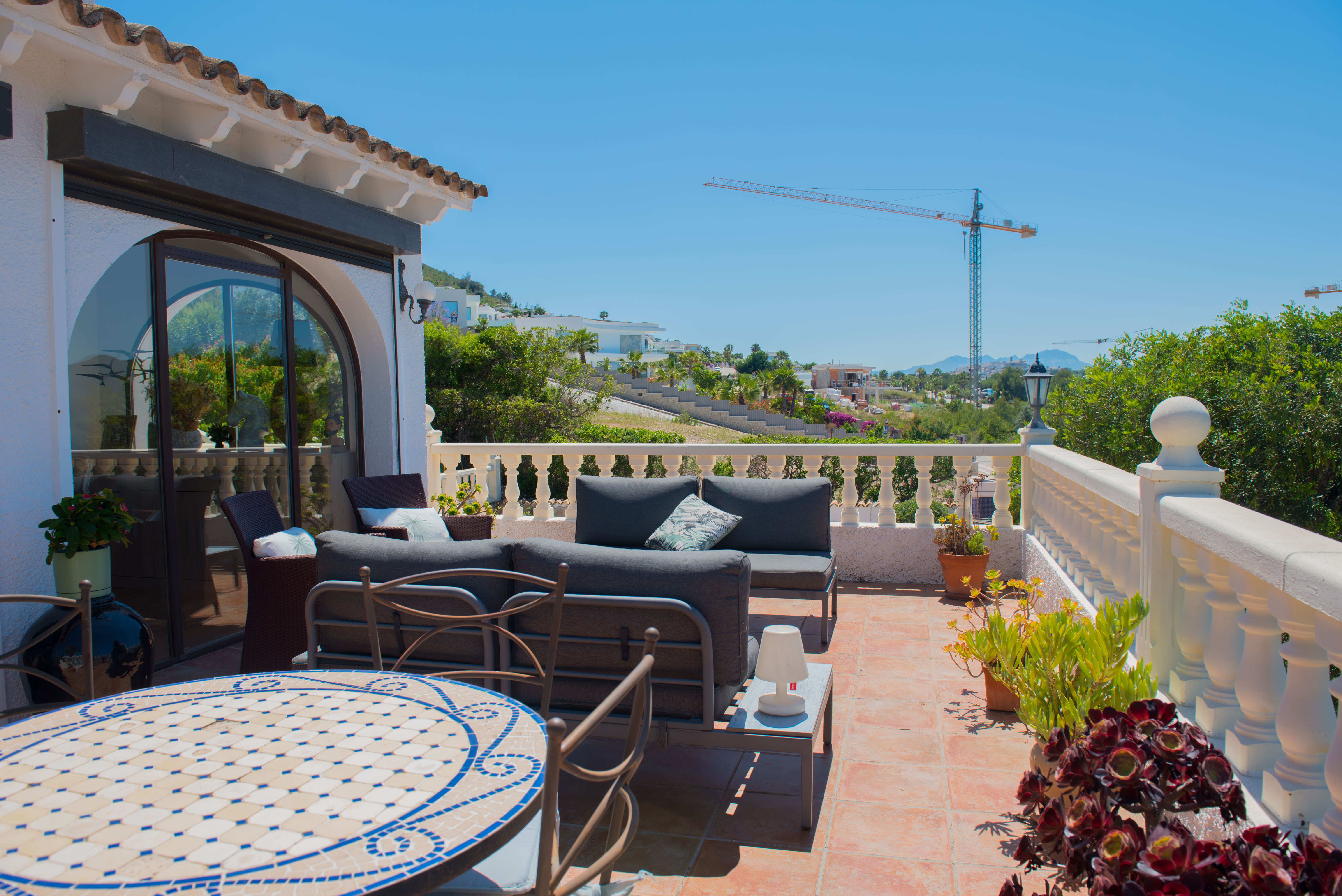 Terrasse avec sol en terre cuite, balustrade blanche et vues panoramiques.