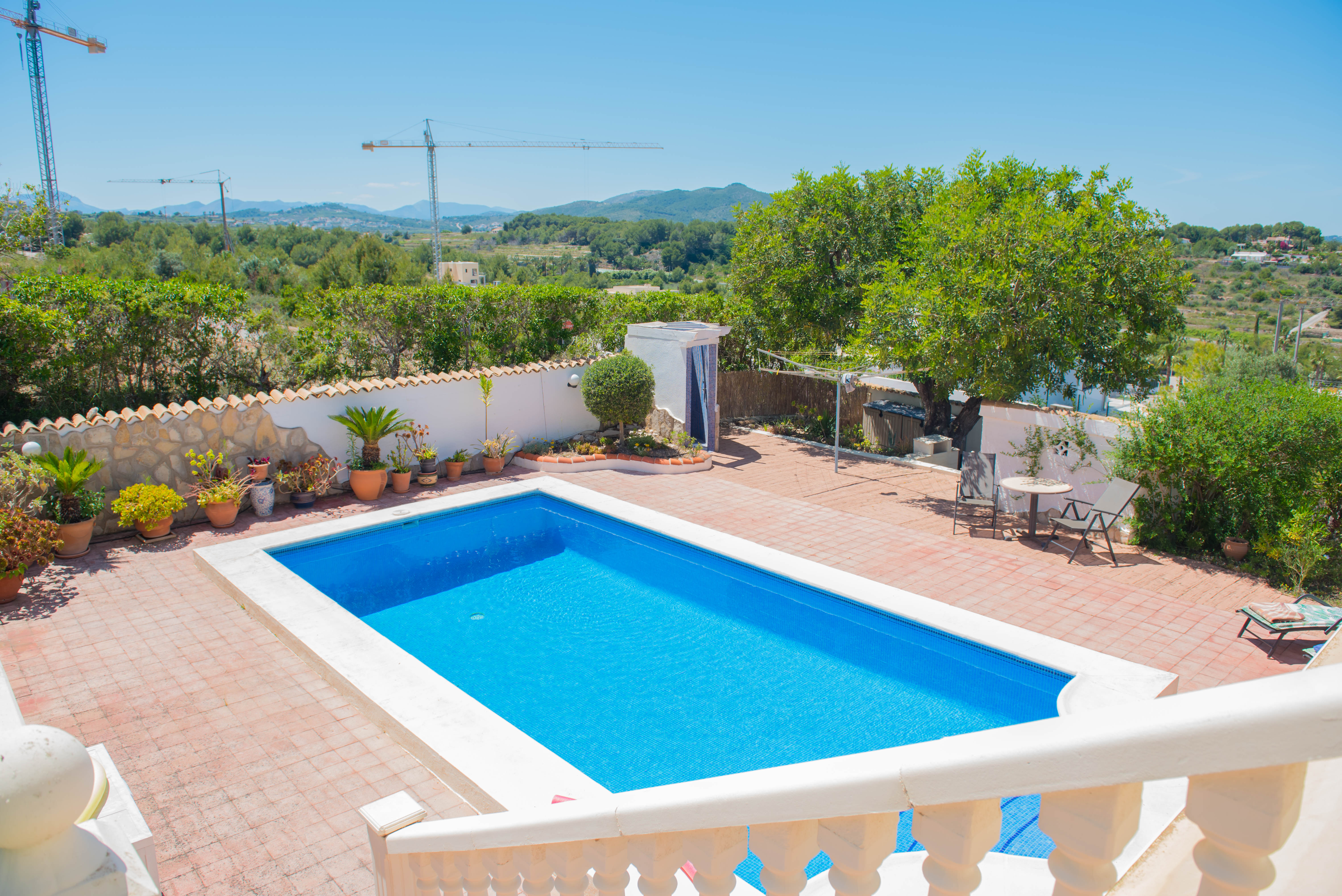 Vue surélevée de la piscine rectangulaire bordée de blanc et terrasse carrelée rouge.