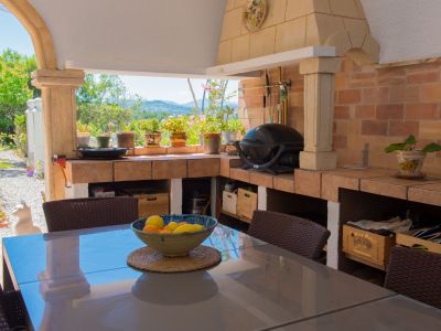 Naya couverte avec cuisine d'été en briques, barbecue intégré et table à manger. Vues sur le jardin luxuriant et les collines au loin.