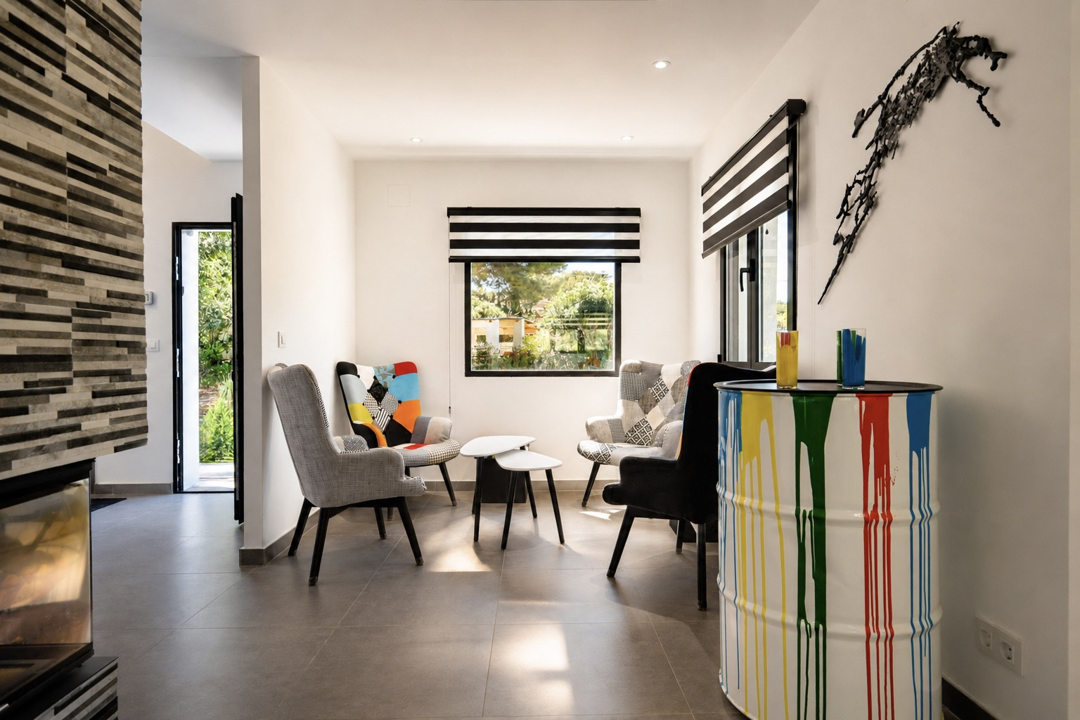 Salon au décor moderne : fauteuils design, table d'appoint et baril décoratif avec peinture.