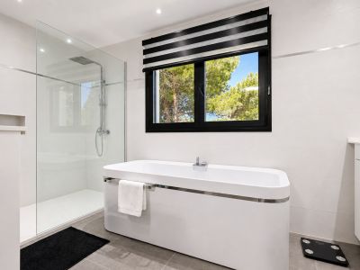 Élégante salle de bain avec baignoire îlot, douche en verre et fenêtre donnant sur l'extérieur.