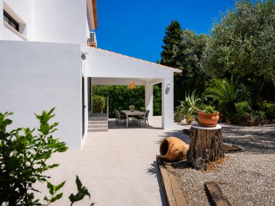 Terrasse couverte avec salle à manger extérieure, entourée d'un jardin méditerranéen et de gravier blanc.