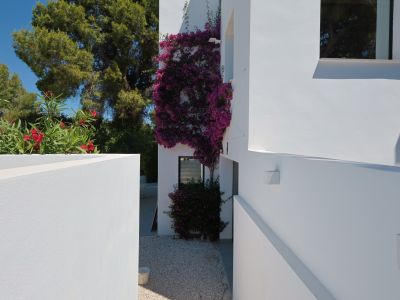 Vue extérieure de la villa, avec des bougainvilliers fleurissant sur la façade blanche et du gravier clair au sol.