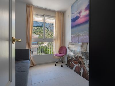 Cette pièce polyvalente dispose d'une fenêtre offrant des vues directes sur la colline verdoyante, complétée par un canapé-lit gris et une chaise de bureau rose. Des œuvres d'art murales ajoutent une touche côtière.