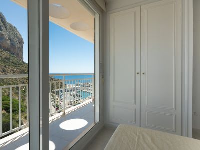Chambre avec élégant placard intégré blanc et accès direct à un balcon privé. Profitez de vues panoramiques sur le port de plaisance, la mer Méditerranée et l'emblématique Peñón de Ifach.