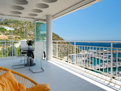 Vaste terrasse avec vues panoramiques sur le port de plaisance, la mer et la montagne. Dotée de rideaux de verre et d'un plafond design à cercles encastrés.