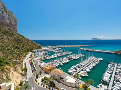 Vue panoramique du port de plaisance animé de Calpe, avec de nombreux yachts sur la mer turquoise et le majestueux Peñón de Ifach à gauche.