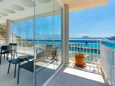Grande terrasse avec fermeture vitrée modulable et espace ouvert, offrant des vues panoramiques directes sur le port de Calpe, la mer turquoise et les côtes lointaines.