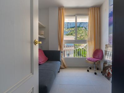 Chambre secondaire ou bureau aménagé avec un canapé, des étagères murales et une fenêtre offrant une vue sur le Peñón de Ifach.