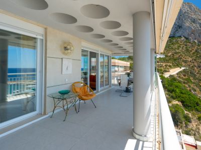 Vaste terrasse couverte offrant des vues panoramiques sur la mer étincelante et l'imposant Peñón de Ifach. Elle présente un plafond distinctif avec des cercles encastrés et un sol carrelé.