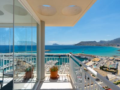 Vaste terrasse vitrée offrant une vue panoramique sur le port de plaisance et la baie de Calpe, avec rideaux de verre coulissants pour en profiter toute l'année.