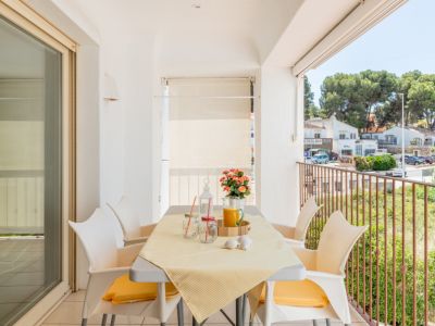 Lumineuse terrasse privée avec table à manger pour quatre, offrant des vues sur la rue et la verdure, accessible par une grande porte coulissante vitrée.