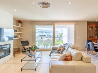 Vaste salon avec canapé en cuir crème, cheminée intégrée et TV murale. De grandes portes coulissantes mènent à une terrasse privée, offrant lumière naturelle et fluidité.