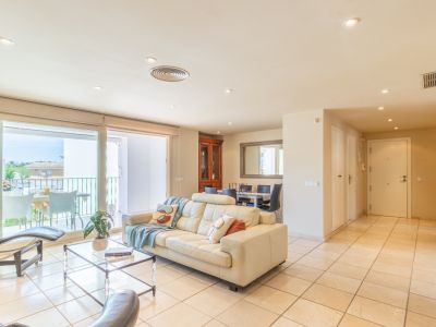 Vaste salon-salle à manger décloisonné avec canapé en cuir crème, accès direct à une terrasse privée, baigné de lumière naturelle et carrelage clair au sol.