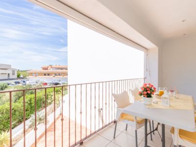 Vaste terrasse privée carrelée avec balustrade métallique, aménagée avec une table et des chaises pour les repas en plein air. Vues sur la verdure et l'architecture locale.