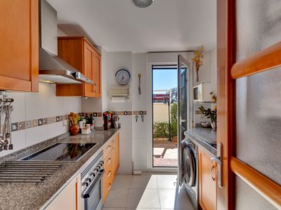 Cuisine fonctionnelle avec des armoires en bois clair, des plans de travail en granit et des appareils en acier inoxydable. Accès direct à un patio extérieur.