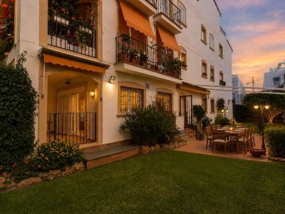 Jardin privé avec pelouse et terrasse carrelée, aménagé pour les dîners extérieurs. La table en bois et l'éclairage ambiant créent une atmosphère chaleureuse au crépuscule.