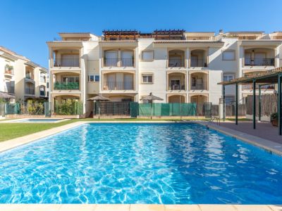 Vaste piscine communautaire d'eau salée, bordée d'une pelouse verdoyante et des bâtiments d'appartements crème avec balcons privés.