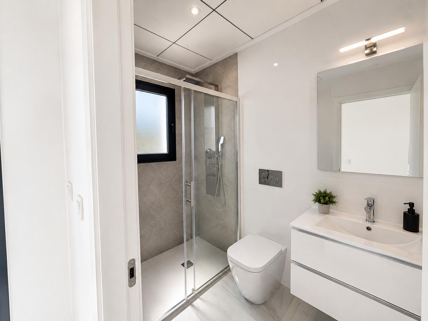 Salle de bain moderne avec meuble-lavabo suspendu blanc, WC mural et douche à l'italienne carrelée de gris texturé avec fenêtre dépolie. Le sol effet marbre complète l'ensemble.