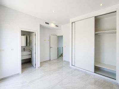 Chambre lumineuse avec sol carrelé en grès cérame clair et armoire intégrée à portes coulissantes. Accès direct à une salle de bain attenante et climatisation gainable.