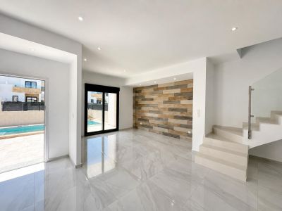 Grand espace de vie avec carrelage en porcelaine polie, mur décoratif à panneaux effet bois et accès direct à la piscine privée. Escalier moderne avec garde-corps en verre.