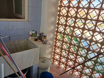 Espace utilitaire avec un grand évier en marbre, carrelage mural bleu et claustra en terre cuite filtrant la lumière naturelle. Potentiel de rénovation.